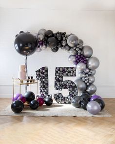 the number fifty five is made out of balloons and helium balls in black, silver, and white colors