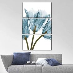 three blue flowers on a white background in a living room with grey sofa and pillows