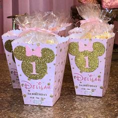 two pink and gold minnie mouse birthday popcorn boxes with bows on them sitting on a counter