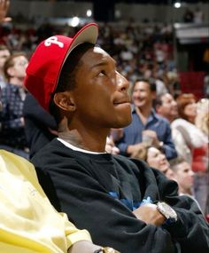 a young man wearing a red hat sitting in front of an audience at a basketball game