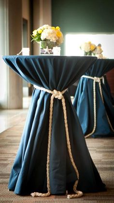 the table is covered with blue cloth and has flowers in vases sitting on it