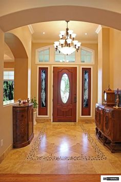 a large foyer with two doors and a chandelier