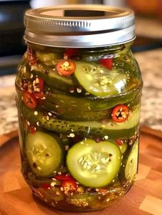 a jar filled with sliced cucumbers on top of a wooden cutting board