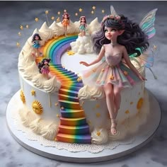 a cake decorated with fairy figurines sitting on top of a rainbow colored staircase