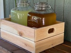 two jars filled with liquid sitting on top of a wooden box