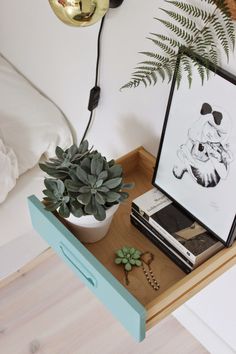 a plant is sitting on a small table next to a framed photo and other items