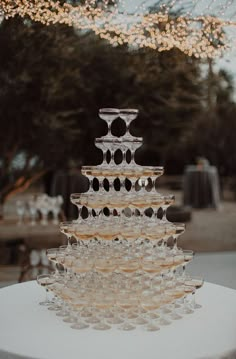 a tall glass cake sitting on top of a white table covered in candles and lights