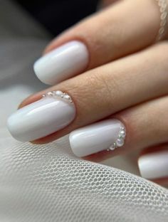 a woman's hand with white nail polish and some beads on her nails,