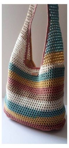 a crocheted purse is sitting on a table next to a white wall and it's handles are made out of multicolored yarn