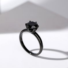 a black diamond ring sitting on top of a white surface with the shadow from it