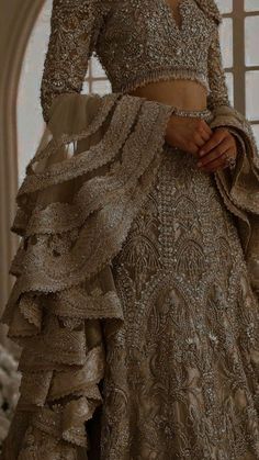 a woman in a wedding dress standing next to a window with her hands on her hips