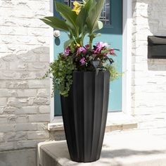 a tall black planter with flowers in it