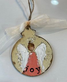 a ceramic ornament with an angel painted on it's face and the word joy