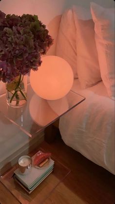 a glass table topped with a vase filled with purple flowers and a candle on top of it