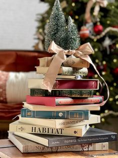 a stack of books sitting next to a christmas tree