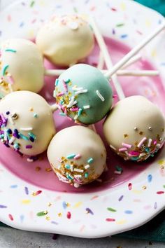 cake pops with sprinkles are on a pink and white plate, ready to be eaten