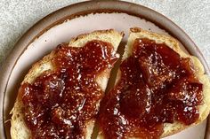 two pieces of bread with jam on them are sitting on a white and brown plate