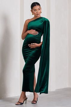 a pregnant woman wearing a green dress and holding a shawl in front of her belly