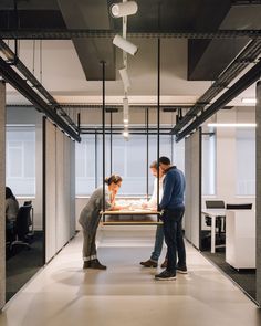 two people standing in an office looking at something on a table that is being held up