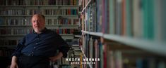 a man standing in front of a book shelf filled with books