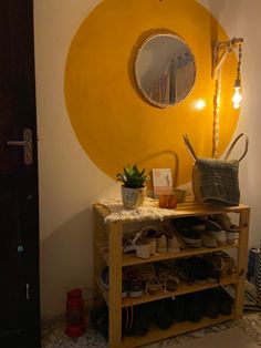 there is a yellow circle on the wall above a shoe rack with shoes and a potted plant