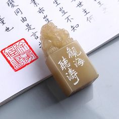 a stamp with chinese writing on it next to a small figurine in front of an open book