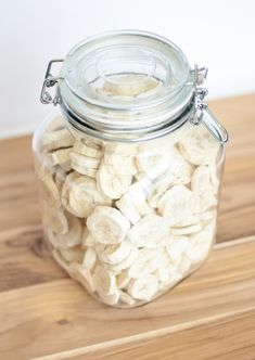 a glass jar filled with sliced bananas on top of a wooden table