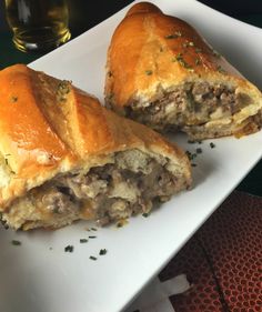 two pieces of meat and cheese pastry on a white plate