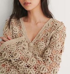 a woman with her arms crossed wearing a crochet sweater