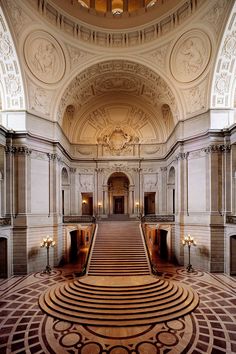 an ornately decorated hall with stairs and chandeliers on either side of it