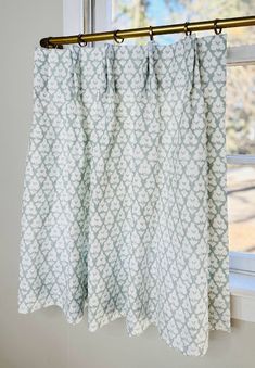 a curtain hanging from a rod in front of a window with white and green curtains