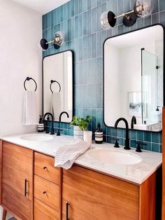 a bathroom with two sinks, mirrors and blue tiles on the backsplashes