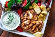 grilled chicken and vegetables on a platter with ranch dressing