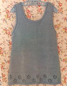 a knitted tank top with holes on the front and bottom, sitting on a floral background