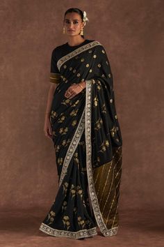 Black silk saree with all over jacquard woven wine garden pattern, floral print, intricate dori, sequin embellished border, contrast tissue patch work pallu border and striped gota work details. Comes with raw silk unstitched blouse piece. Components: 2 Pattern: Woven, Embellished and Printed Type Of Work: Wine Garden Pattern, Floral Print, Gota, Dori and Sequin Work Fabric: Saree: Silk, Blouse Piece: Raw Silk Color: Black Other Details:  Gota cut work hem details Note: The stitched blouse worn Black Silk Saree, Sitara Work, Wine Garden, Jacquard Saree, Gota Work, Patch Work Blouse, Garden Pattern, Saree Silk, Black Saree