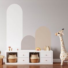 a toy giraffe standing next to a white cabinet with baskets on the bottom