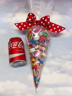 a candy bag with a red polka dot bow next to a can of coca - cola