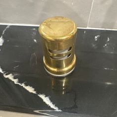 a metal object sitting on top of a black table next to a white tile wall