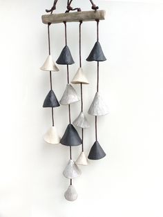 a wind chime hanging on the wall with several different shades of gray and white