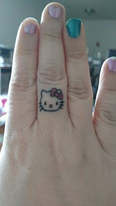 a woman's hand with a hello kitty tattoo on the middle finger and a bow in the middle