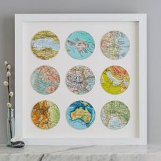 a white frame with six different maps on it and a vase in the corner next to it