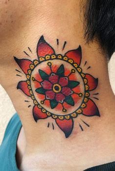 a woman's neck with a colorful flower tattoo on the back of her neck