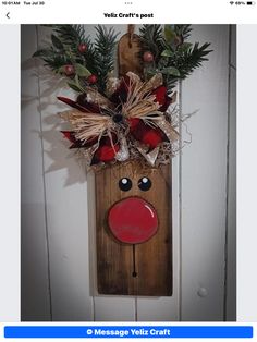 a wooden reindeer head hanging on the side of a door with holly and red berries