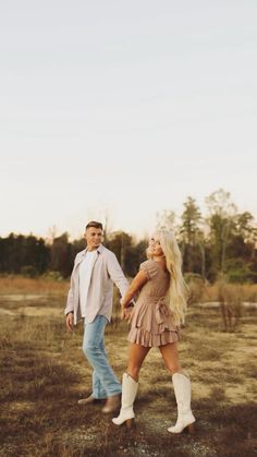 a man and woman holding hands in an open field