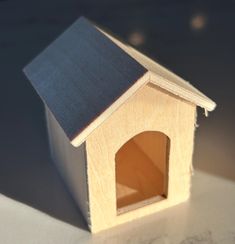 a small wooden birdhouse with a blue roof sits on a white countertop next to a gray wall