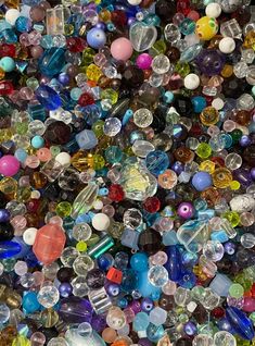 many different colored glass beads are piled on top of each other in the same pattern