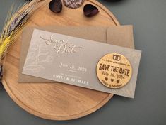 save the date magnets on top of a wooden plate next to some dried flowers