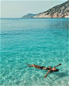 a woman floating in the ocean on top of a body of water