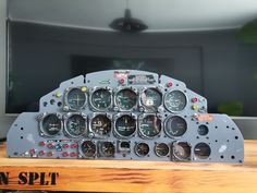 an old airplane cockpit with multiple gauges and dials on the front, sitting on a wooden table