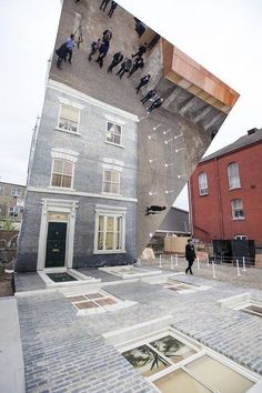 an upside down building with people standing outside